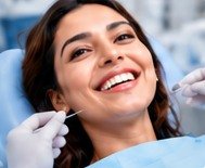 Happy patient with a bright smile reclining in the dental chair